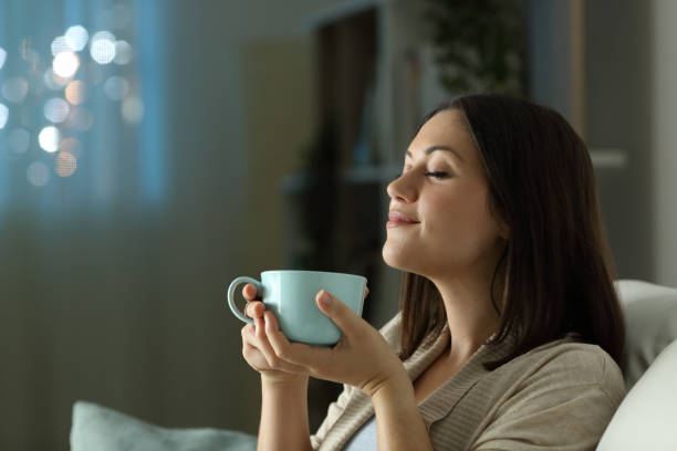 femme relaxant sentant le café dans la nuit à la maison - in the evening photos et images de collection