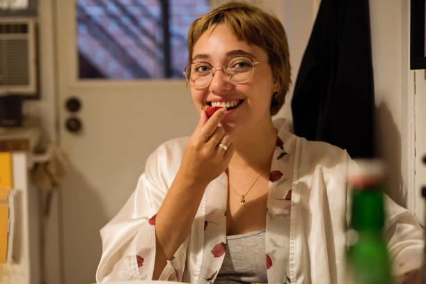 istock Young woman eating a strawberry in kitchen at dawn. 1277431599