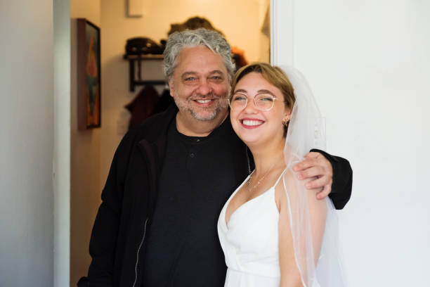 Millennial future bride and her father getting ready for wedding. Millennial future bride and her father ready to go to the wedding celebration. Part of a series. She has short hair and is wearing eyeglasses. Horizontal waist up indoors shot with copy space. bride hugging father on wedding day stock pictures, royalty-free photos & images