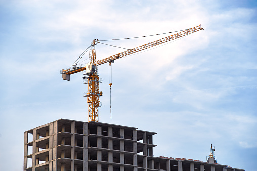 Construction site with crane at cloudy blue sky