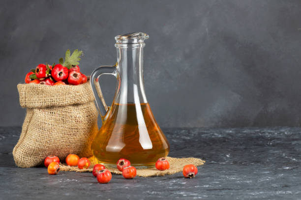 Glass bottle of hawthorn vinegar with Fresh ripe red/yellow hawthorn fruits on rustic background. Crataegus monogyna berries Glass bottle of hawthorn vinegar with Fresh ripe red/yellow hawthorn fruits on rustic background. Crataegus monogyna berries hawthorn photos stock pictures, royalty-free photos & images