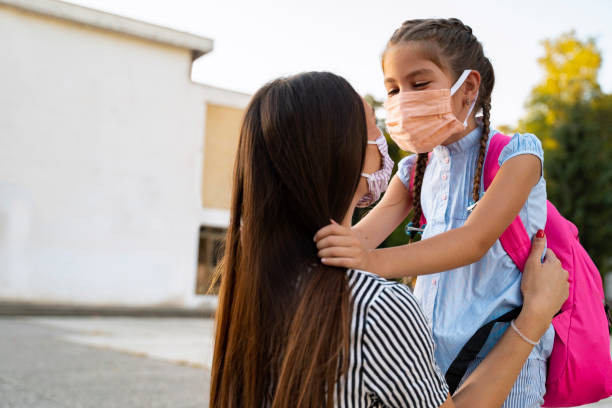 istock Happy kid hugging her mother after school, with face mask on 1277449353