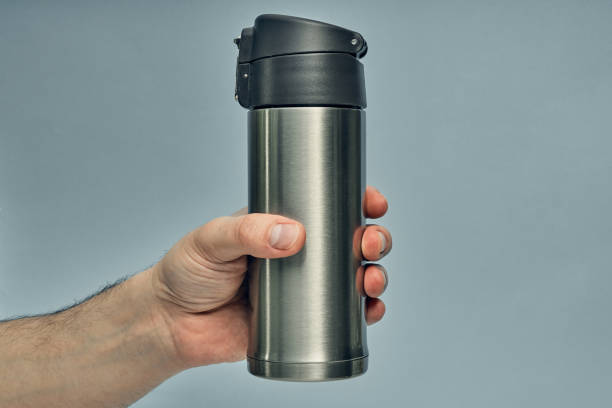 istock Metal mug thermos in hand on a colored background. Hot drinks on the go. Thermo mug. 1277452955