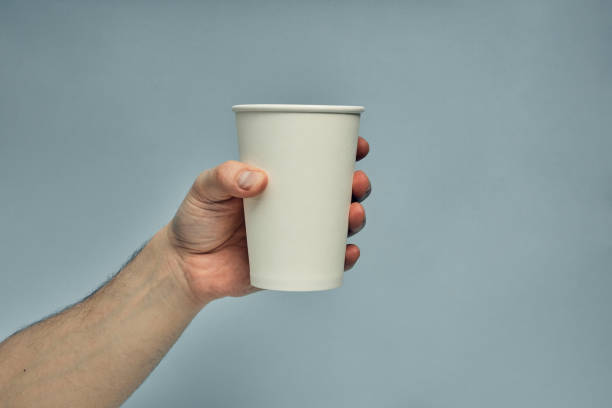 istock Paper cup in hand on a colored background. Eco-friendly materials in a coffee shop, biodegradable disposable tableware. Close up 1277452962