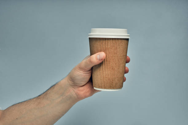 istock Paper cup in hand on a colored background. Eco-friendly materials in a coffee shop, biodegradable disposable tableware. Close up 1277452963