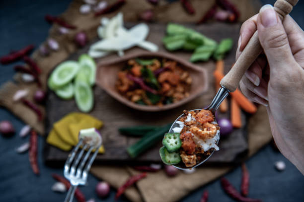istock The hand is using a spoon to scoop Pork Crackling Chili Paste with fried kaffir lime leaves with the ingredient and fresh vegetables on wood background. 1277453821