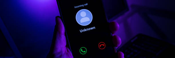 istock Man holding cell phone receiving unknown call - Background with computer screen and blue neon light with lilac 1277458350