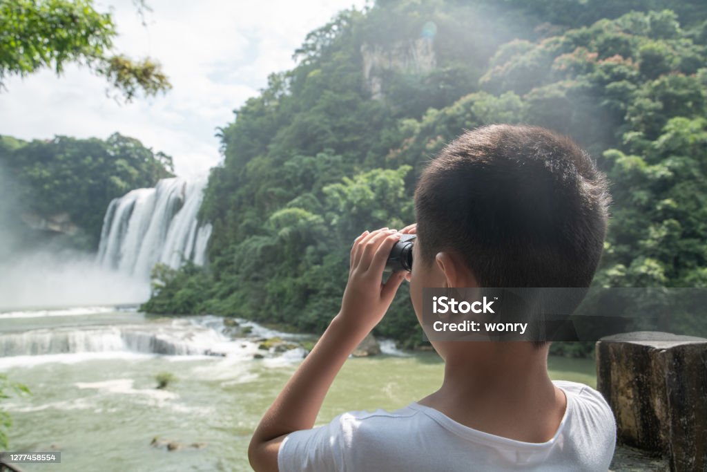 Cute boy looking at waterfall with binoculars Asia Stock Photo