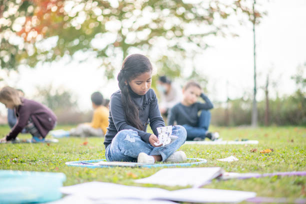 istock Kids sitting in hula hoops on the ground in a modified outdoor classroom 1277458567