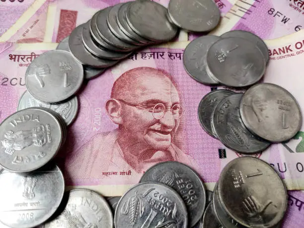 two thousand rupees bank note with coins on it showing mahatma gandi image on currency