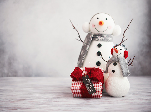 Merry christmas and happy new year greeting card . Happy snowman standing with christmas gifts on gray background