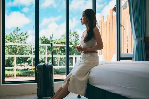 Young Asian female traveller by the window in a hotel room