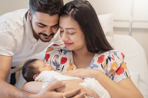 Asian parents with newborn baby, Closeup portrait of asian young couple father mother holding new born baby in hospital bed. Happy asia lovely family, nursery breastfeeding motherâs day concept