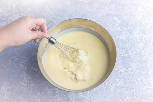istock Cooking lemon pie or semolina cake. Woman's hand holding whisk  blending mix for bakery in metall bowl with whisk. Homemade food concept. 1277478695