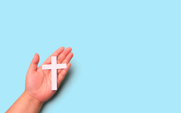 istock Crucifix cross in hand on blue background in studio. 1277480774