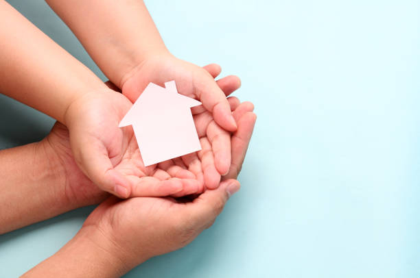 istock hands holding paper house on blue background. 1277482887