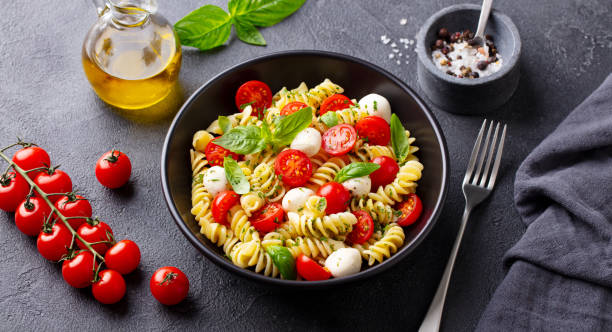 istock Pasta fusilli with mozzarella cheese, tomatoes and basil. Grey background. Close up. 1277483143