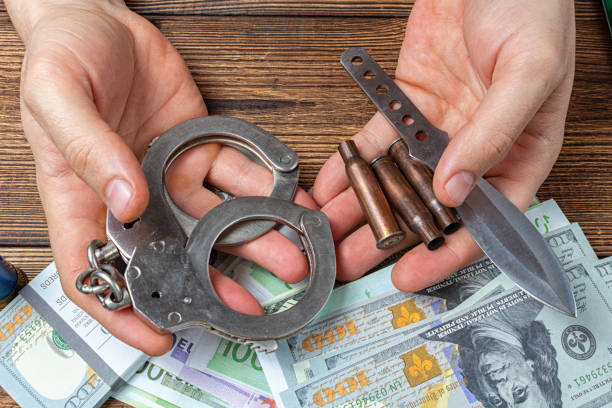 istock hands with handcuffs, knife and ammunition with money banknotes. 1277483250