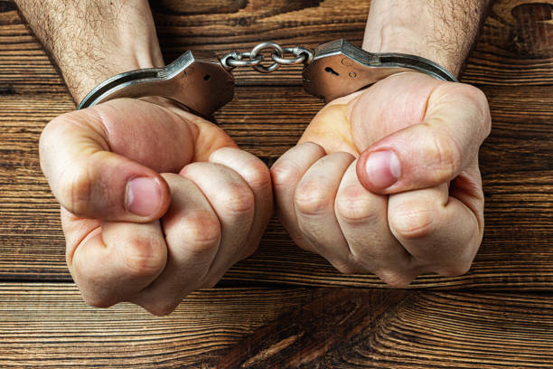 istock hands in handcuffs on the dark wooden background 1277483275