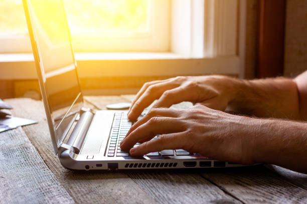 istock hands of a man working at a computer laptop by the window in the sunlight 1277483854