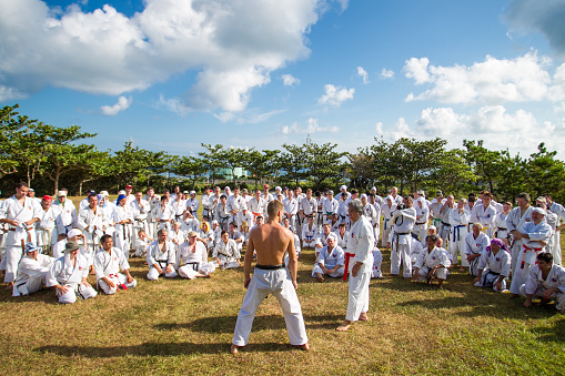 On August/12/2013 in a park in Yomitan, Okinawa a traditional Okinawa Karate master is teaching many students both local and from around the world. Okinawa is the birth place of Karate. Many practitioners travel from all around the world to study Karate in Okinawa each year. And if lucky will get to meet a Karate master.