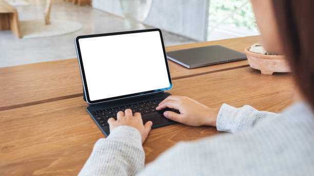 istock a woman using and typing on tablet keyboard with blank white desktop screen as a computer pc on the table 1277485450