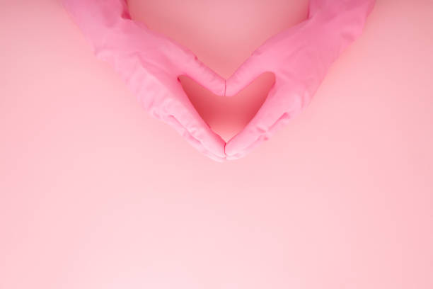 istock Cleaner hands in rubber protective gloves showing heart shape on light pink table background. Pastel color. Closeup. Empty place for text. Top down view. 1277487738