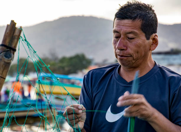Puerto Lopez, Ecuador - Aug 19, 2016: Fisherman repairs his fishing nets in Puerto Lopez, Ecuador