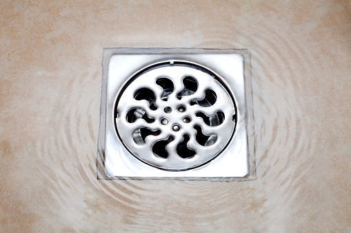 water flowing over into metal drain on the tiled floor of a shower