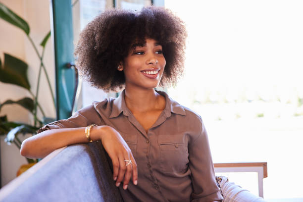 istock Smiling young woman sitting on couch in a cafe 1277497643