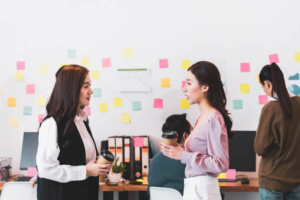 istock Chatting between colleagues,Two young employees standing in modern office, discussing project, smiling sharing news during break at work, talking, having pleasant conversation before the start of work 1277498364
