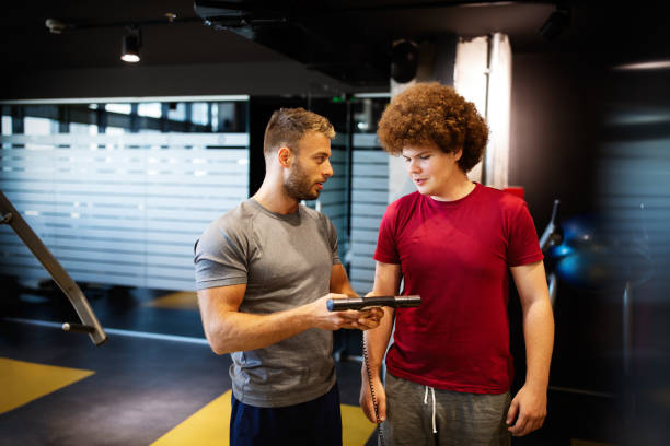 istock Overweight young man exercising gym with personal trainer 1277499126