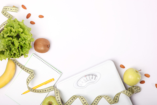 floor scales, tape measure and healthy products on a colored background top view. The concept of a healthy diet, body weight control. Healthy lifestyle.