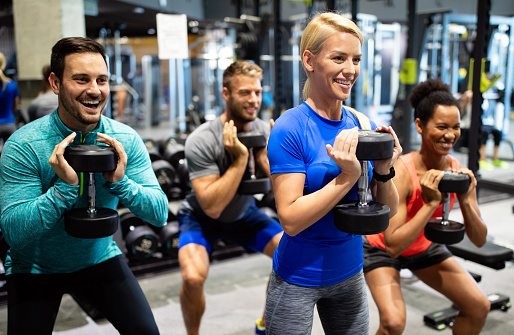 Group of sportive people in a gym training. Multiracial group of friends working out together in fitness club