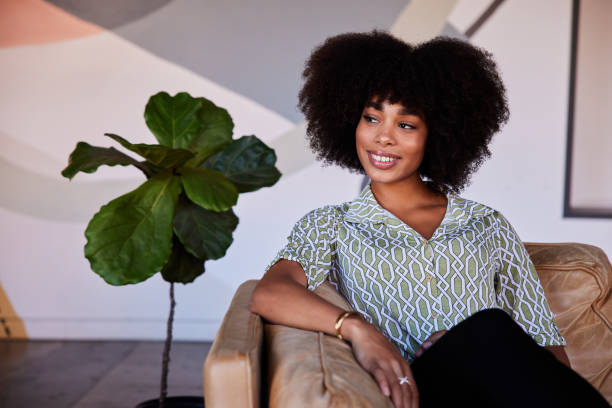 istock Smiling young woman sitting on couch in a cafe 1277499234