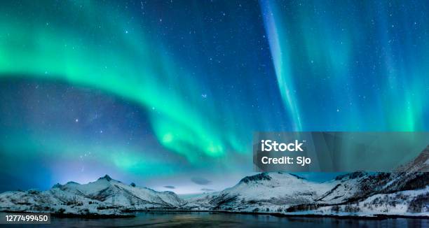 Aurora Borealis Over In The Dark Night Sky Over The Snowy Mountains In The Lofoten Stock Photo - Download Image Now