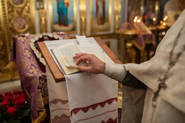 Photo of Hands of christian orthodox priest reading a bible.