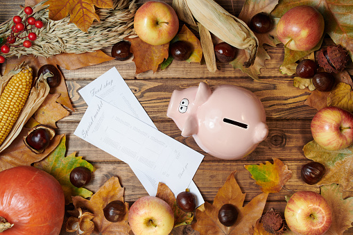 Hello autumn. autumn background with wheat heads, corn, piggy bank, store receipts, pumpkin, apples, rowan, chestnuts and leaves on wooden planks.