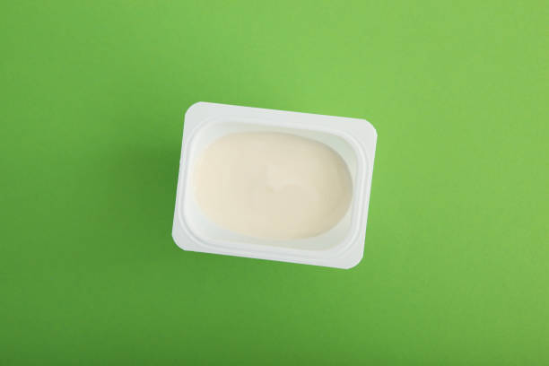istock Tasty yogurt in a plastic glass on a colored table top view. Place to insert text. Useful snack. 1277502746