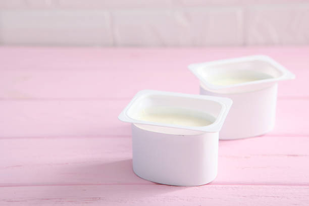 istock Tasty yogurt in a plastic glass on a colored table top view. Place to insert text. Useful snack. 1277502759