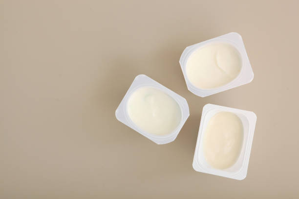 istock Tasty yogurt in a plastic glass on a colored table top view. Place to insert text. Useful snack. 1277503341