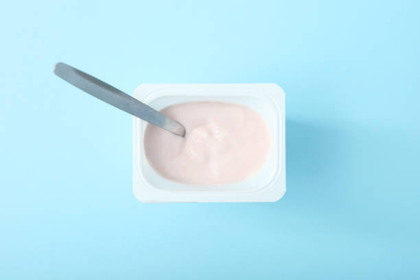 istock Tasty yogurt in a plastic glass on a colored table top view. Place to insert text. Useful snack. 1277503691