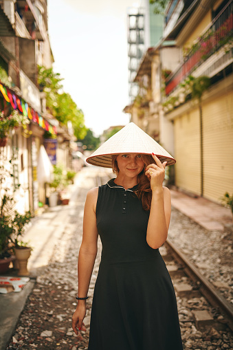 Shot of a young woman wearing a conical hat while exploring a foreign city