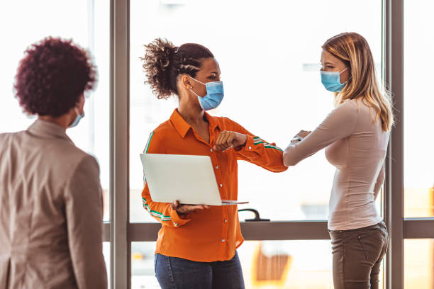istock Female colleagues with face masks elbow bumping while greeting in the office. 1277514043