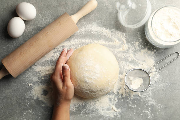 istock Female hand hold dough on gray background with ingredients for baking 1277514128