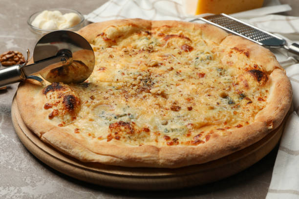 istock Pizza cutter and cheese pizza, close up 1277515499