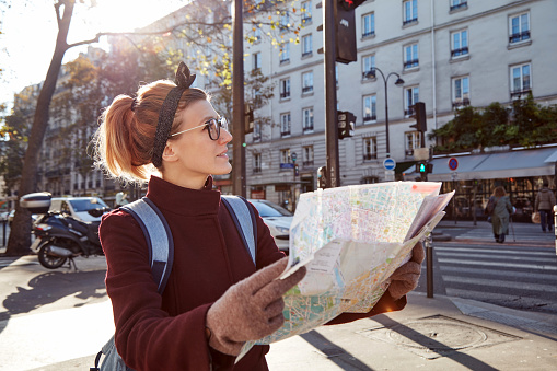 Woman tourist using city map in Paris streets, France.
