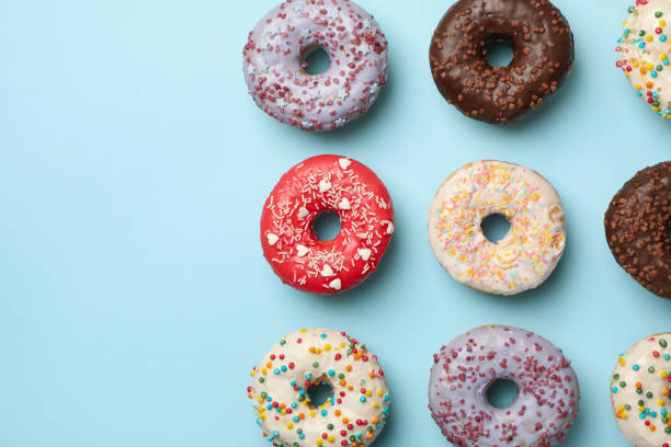 istock Flat lay with tasty donuts on blue background 1277516858