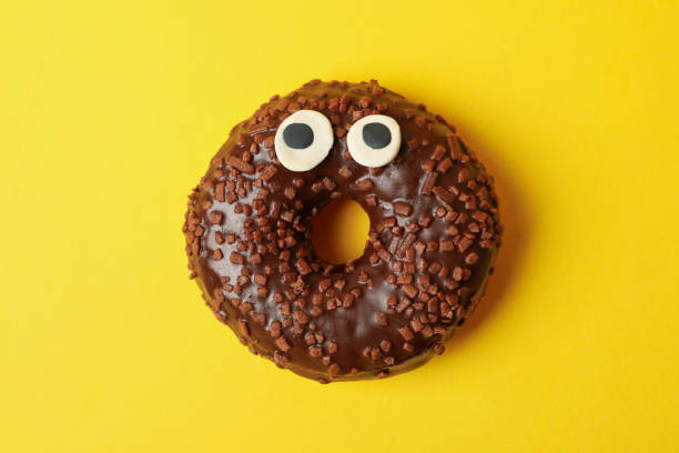 istock Tasty chocolate donut with eyes on yellow background 1277516880