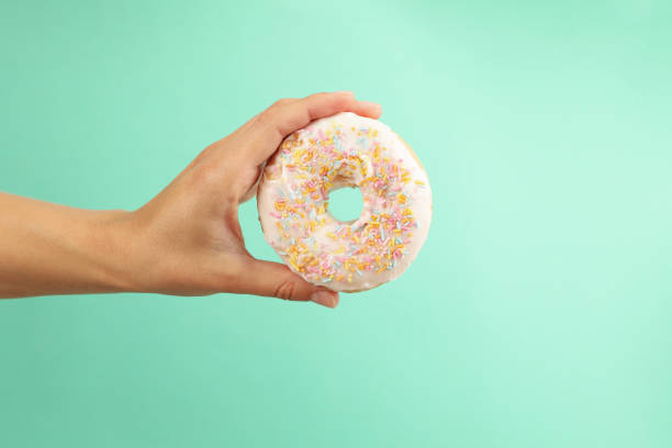 istock Female hand hold tasty donut on mint background 1277517057